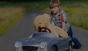 Child in childs car with teddy