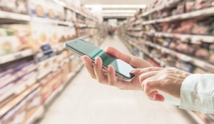 Person holding phone in supermarket aisle