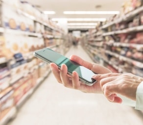 Person holding phone in supermarket aisle